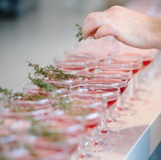 Hand placing rosemary in cocktails