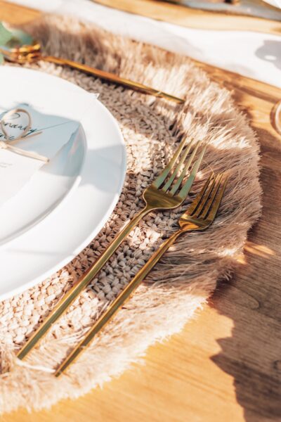 Table setting with rattan place mat and gold cutlery